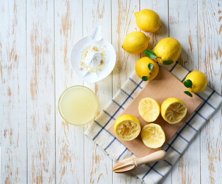 Making lemon juice from ripe lemons. Freshly squeezed lemon juice on a white table, top view.