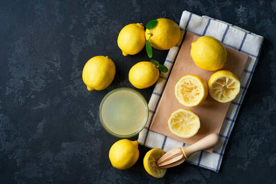 Freshly squeezed lemon juice on a dark table, top view. Making lemon juice from ripe lemons.