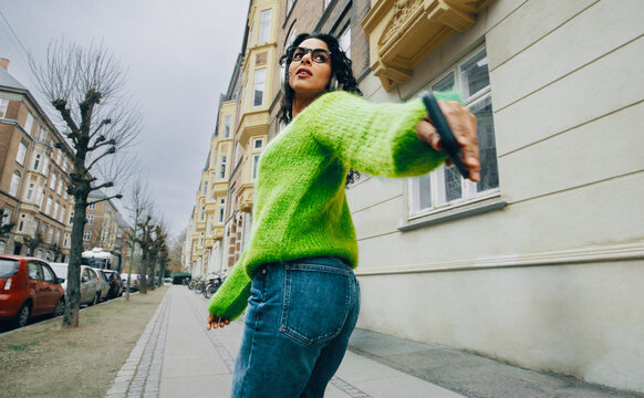 Woman walking in the city with smartphone streaming music on the go
