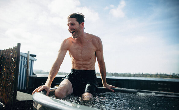 Man exiting ice bath outdoors for cold recovery and wellness therapy