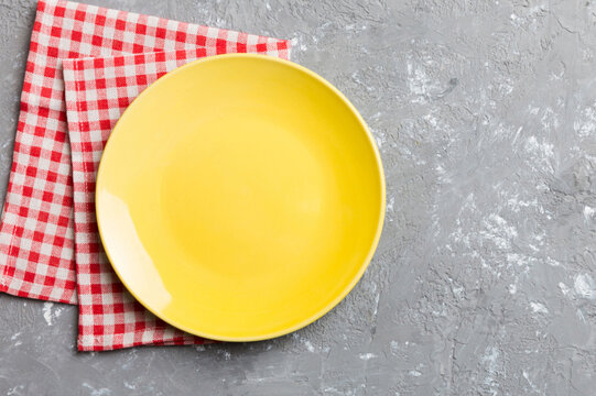 Top view on colored background empty round yellow plate on tablecloth for food. Empty dish on napkin with space for your design