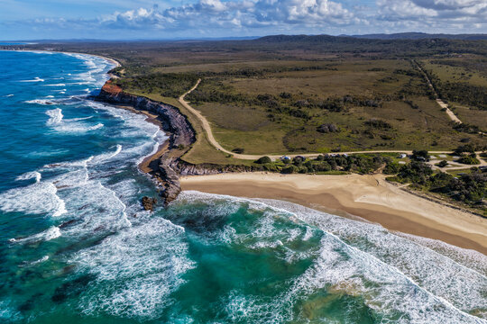 Aerial view of Lake Arragan Beach and campground on the NSW North Coast, featuring the sandy shoreline, coastal camping area, native bushland and Pacific Ocean within Yuraygir National Park, Australia