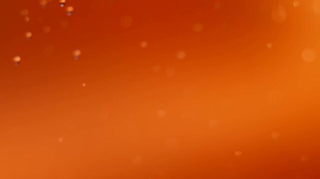 Orange bubbles suspended in glowing liquid with soft light and abstract background