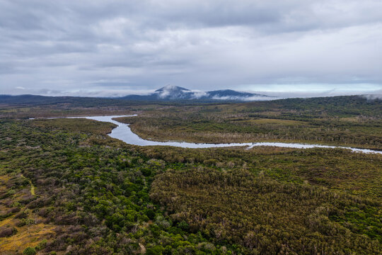 Aerial view of the Lake Arragan estuary surrounded by native coastal vegetation and natural landscape beneath a cloudy sky within Yuraygir National Park on the NSW North Coast, Australia.
