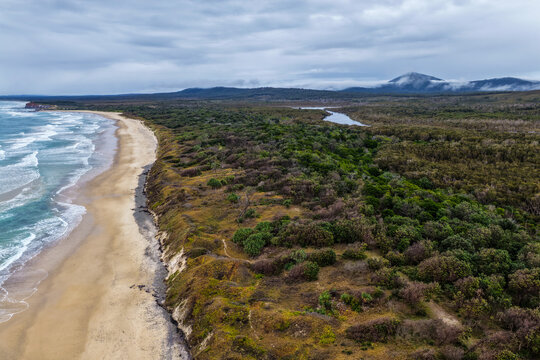 Aerial view of Lake Arragan Beach and Lake Arragan within Yuraygir National Park, showcasing the sandy Pacific coastline, coastal lake, native bushland and surrounding natural landscape 
