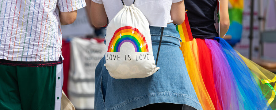 Participant carries white drawstring bag with rainbow graphic and Love is Love message during CSD event in Magdeburg. Colorful symbols represent LGBTQ visibility, equality, diversity and acceptance