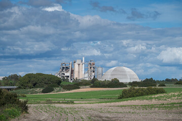 Cement factory and industrial facilities surrounded by agricultural fields under dramatic cloudy sky in Cadiz province, Andalusia, Spain © ihervas