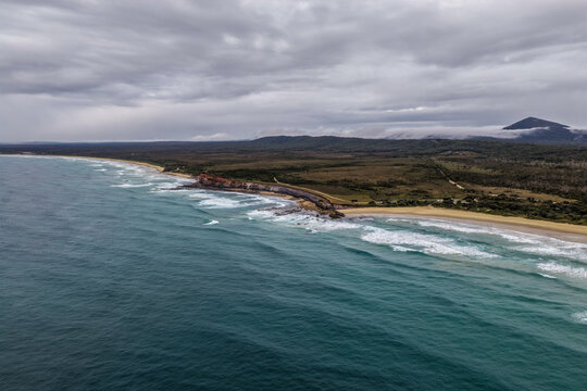 Aerial view of Lake Arragan Beach and the surrounding coastal landscape, featuring a long sandy shoreline, Pacific Ocean, native bushland and pristine natural scenery within Yuraygir National Park