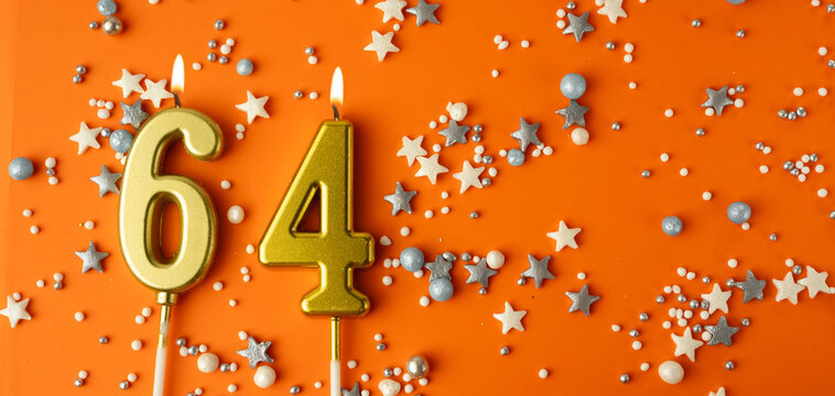 Birthday or anniversary celebration concept. Candles in the shape of the number sixty-four on an orange background among decorative ornaments. 64th anniversary. Banner
