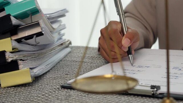 Legal Professional Signing Documents with Scales of Justice in Law Office