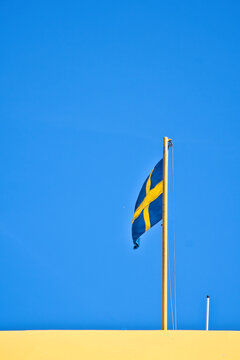 Swedish Flag Waving on Flagpole Against Clear Blue Sky