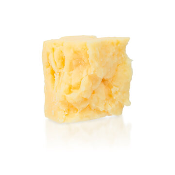 Block of yellow cheese with a slightly crumbly texture on a white background, showcasing its rich color and natural imperfections