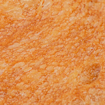 Close-up view of textured bread crust showcasing golden brown color and irregular surface patterns, highlighting the artisanal quality of freshly baked bread