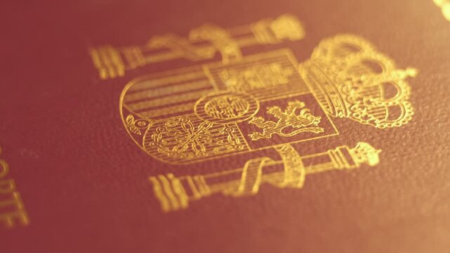 Rotating close-up of a Spanish passport cover with the golden national coat of arms.