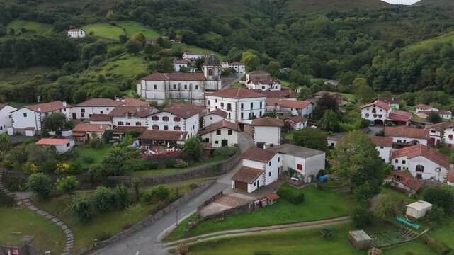 Aerial drone orbit shot panning left around the historic church in Zugarramurdi village, Navarra, Spain