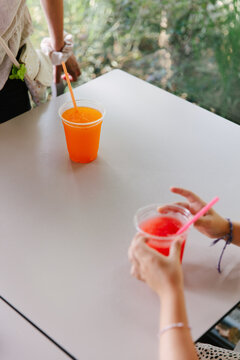 two colorful drinks with kids hands on a table