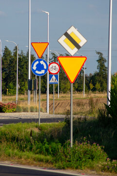 Road traffic signs at a roundabout in Poland, including give way, priority road and bicycle signs