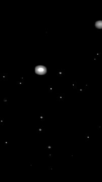 White Particles Flying Through Black Space. Glowing particles rush toward the camera, recede and drift randomly across a dark background.