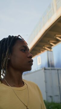 Vertical video of African American young adult with dreadlocks walking outdoors in urban area. Footage is suitable for youth lifestyle marketing and modern diversity campaigns