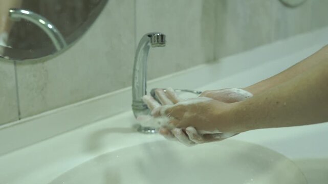 Washing Hands with Soapy Foam in Bathroom Sink Close Up