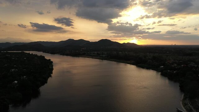 Aerial drone view of Thien Mu Pagoda and the Perfume River at sunset in Kim Long Ward, Hue, Vietnam, showcasing a historic landmark and scenic riverside landscape.