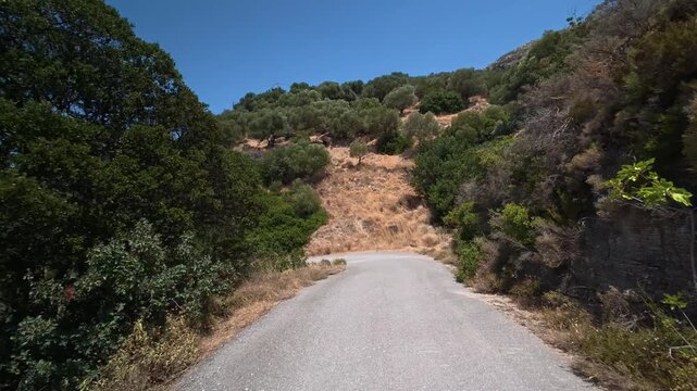 A car drives slowly along a dangerous winding mountain road on the island of Crete, Greece.