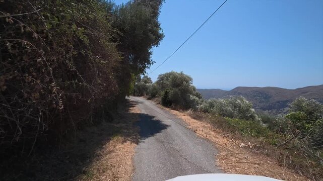 A car drives slowly along a dangerous winding mountain road on the island of Crete, Greece.