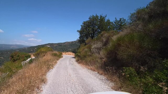 A car drives slowly along a dangerous winding mountain road on the island of Crete, Greece.