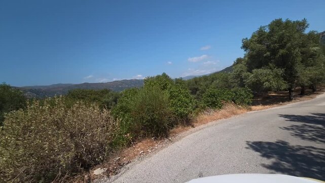 A car drives slowly along a dangerous winding mountain road on the island of Crete, Greece.