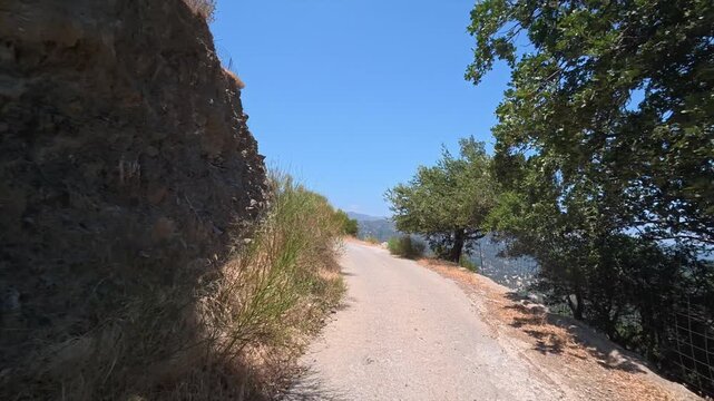 A car drives slowly along a dangerous winding mountain road on the island of Crete, Greece.