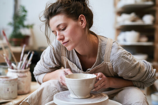 A skilled artisan shapes a coffee cup on a pottery wheel, embodying the beauty of craftsmanship and the unique connection between creator and creation.