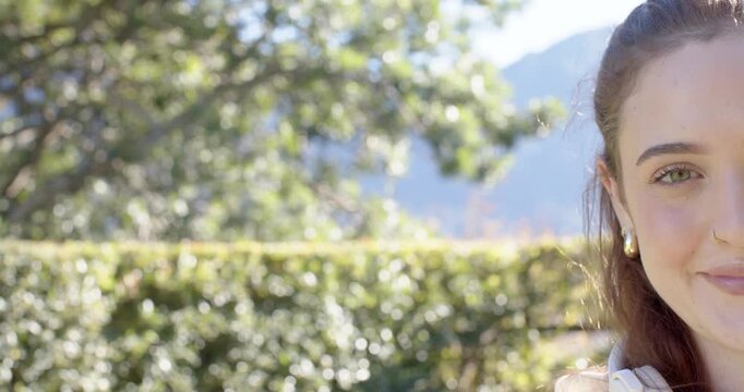 Adult female starting offframe in garden, opening eyes and smiling with white headset, copy space