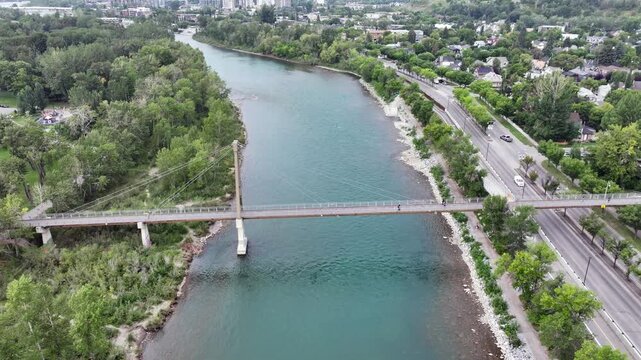 flying backwards above Bow River next to Prince&rsquo;s Island Park, away from Bow River Pathway Bridge, located next to Downtown Calgary ( Alberta, Canada) - 4k aerial video footage 