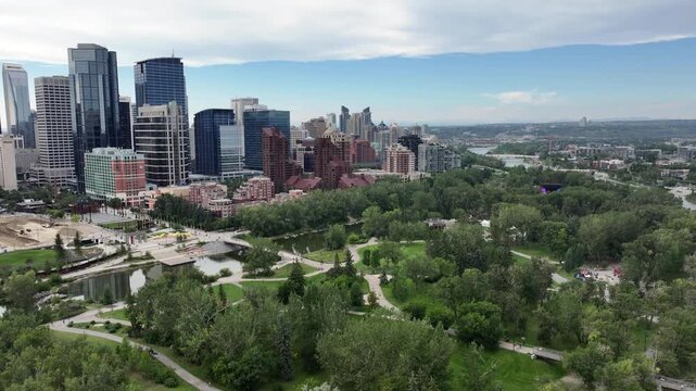 panning left along Skyline of Downtown Calgary ( Alberta, Canada)  to Centre St Bridge, with Prince&rsquo;s Island Park and Bow River below and skyscrapers in front - 4k aerial video footage 