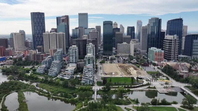 flying along Skyline of Downtown Calgary ( Alberta, Canada) and panning left  to Centre St Bridge, with Prince&rsquo;s Island Park and Bow River below - 4k aerial video footage 
