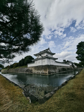 View of the historic Nijo Castle corner turret and stone walls rising above the surrounding moat under a cloudy sky in Kyoto, Kyoto, Japan.