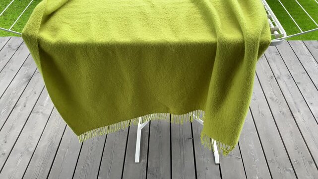 Soft Green Blanket Draped Over a Drying Rack in a Bright Outdoor Setting