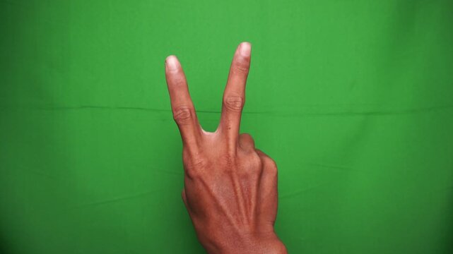 Hand Making a Peace Sign or Victory Gesture Against a Green Screen