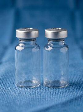 Two Empty Sterile Glass Medication Vials on Blue Surgical Cloth