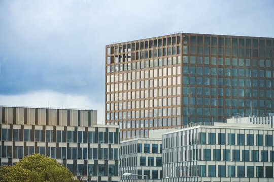 View of modern office buildings with glass facades and grid patterns under a cloudy sky in Poznan, Greater Poland Voivod, Poland.