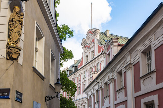 View of a historic street in Poznan featuring a statue of the Virgin Mary on a corner building, ornate architecture, and colorful facades in Poznan, Greater Poland Voivod, Poland.