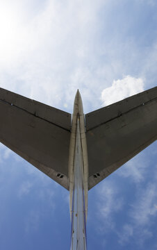 Part of aircraft tail and sunlit blue sky with clouds