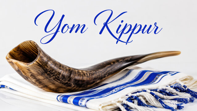 Curved shofar displayed on folded tallit beneath yom kippur script, religious greeting banner, jewish prayer plus forgiveness message