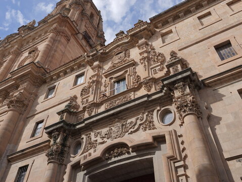 View of the ornate facade and tower of the New Cathedral of Salamanca with intricate stone carvings against a blue sky in Salamanca, Castile and Leon, Spain.
