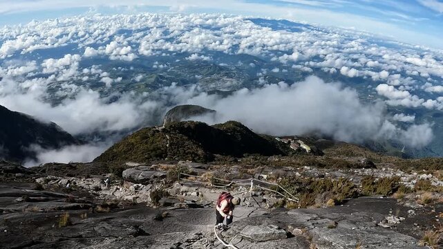Female tourist while descending from Mt.Kinabalu summit by rappelling. Mt.Kinabalu is the highest mountain in Borneo and Malaysia.