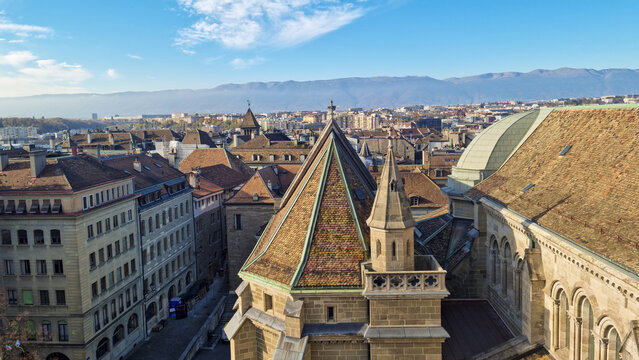 View of the historic St. Pierre Cathedral rooftops with terracotta tiles and stone spires overlooking the urban cityscape of Geneva, Geneva, Switzerland.