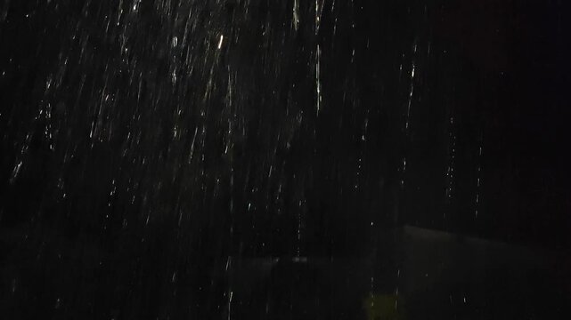 Heavy rain falling at night during a powerful storm, with faint flashes of lightning visible through the darkness, creating a dramatic and atmospheric weather background.