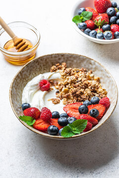 Granola bowl with greek yogurt, berries and honey for healthy breakfast.