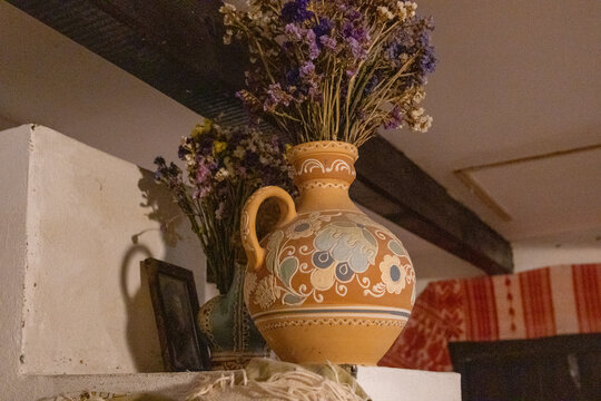 Traditional decorated clay jug with dried Sea lavender (Limonium) flowers in a rustic whitewashed interior