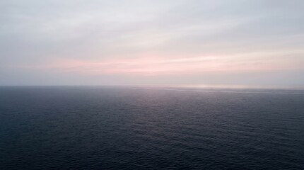 Obraz premium Soft Pink Sunrise Over Calm Sea Horizon Minimalist Ocean View. Concept of water, sky, landscape, calm water, serene landscape, tranquil sea. Copy space.